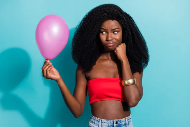 Photo portrait of girl in top unhappy angry looking at pink air balloon isolated vivid blue color background